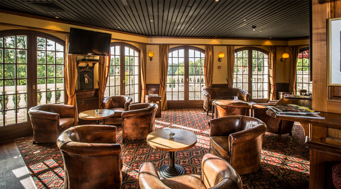 leather tub chairs and small wooden round tables spread across the bar seating area, surrounded by large french doors